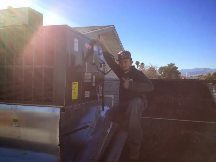 HVAC technician performing AC Tune-Up on a rooftop unit in Hyrum